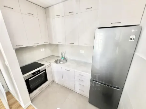 Small equipped kitchen with light-colored cabinetry and a refrigerator. - image 4
