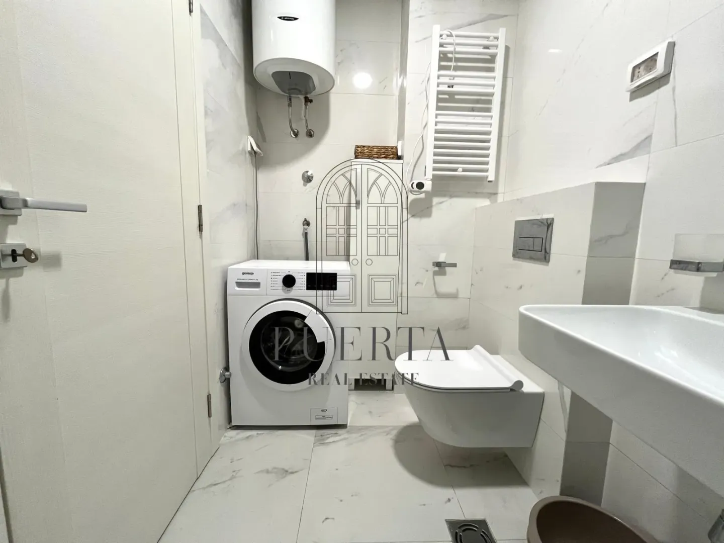 Modernly equipped bathroom with white tiles, washing machine, and sanitary fixtures.