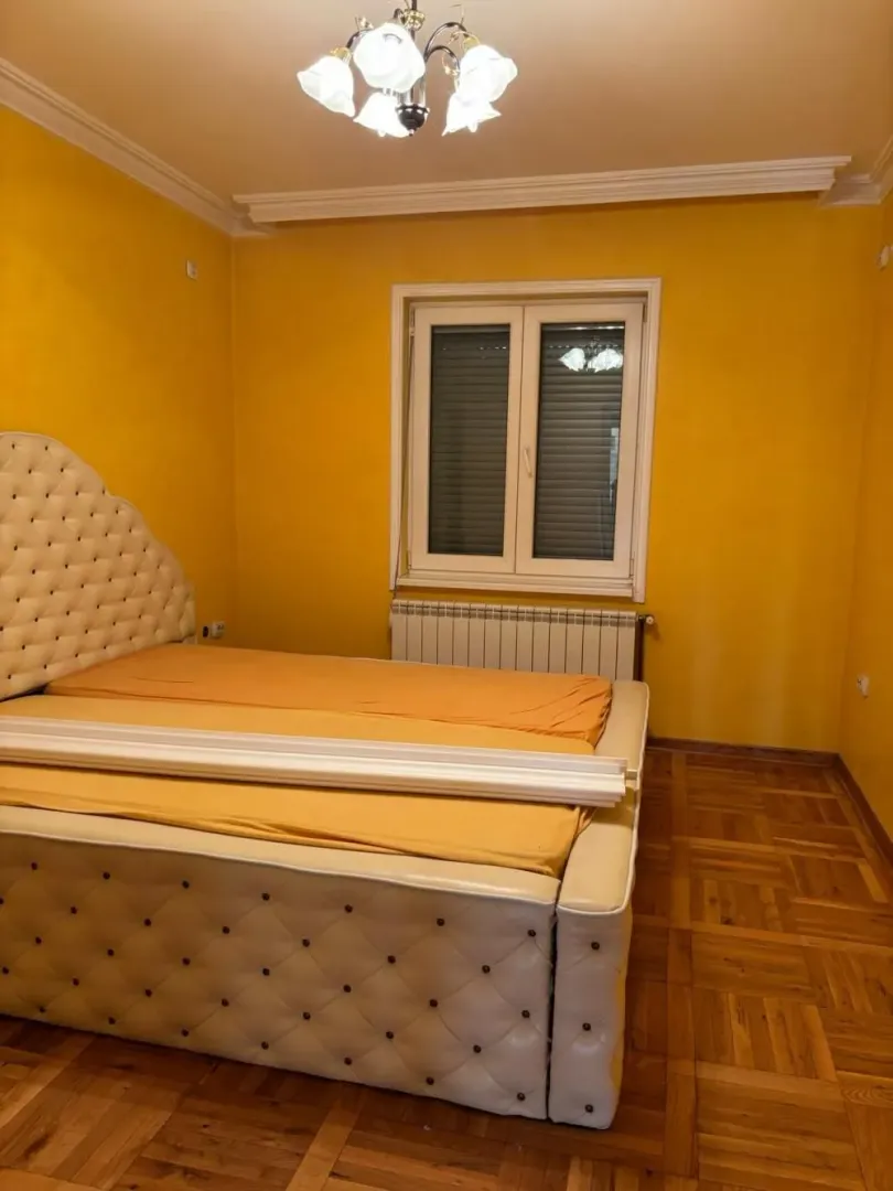 Bedroom with a double bed, yellow walls and parquet flooring.