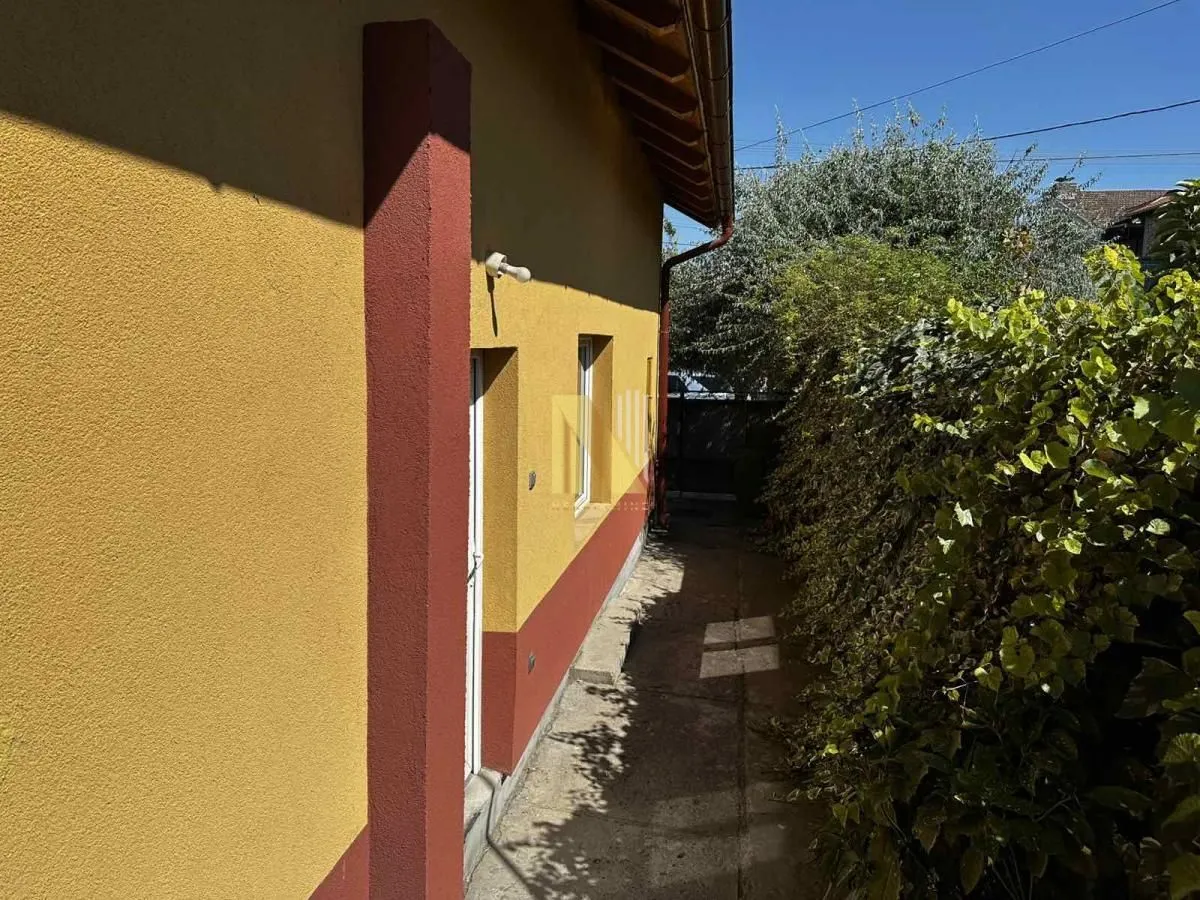 Bočna strana kuće sa prolazom i zelenilom.