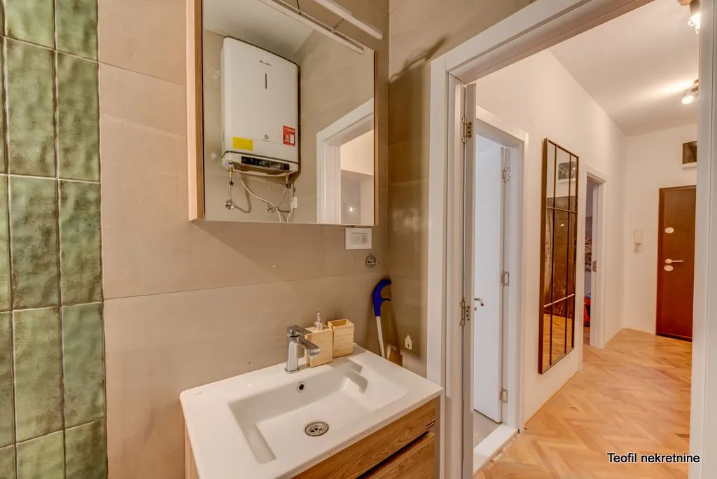 Bathroom with sink, mirror and water heater, looking towards the hallway.