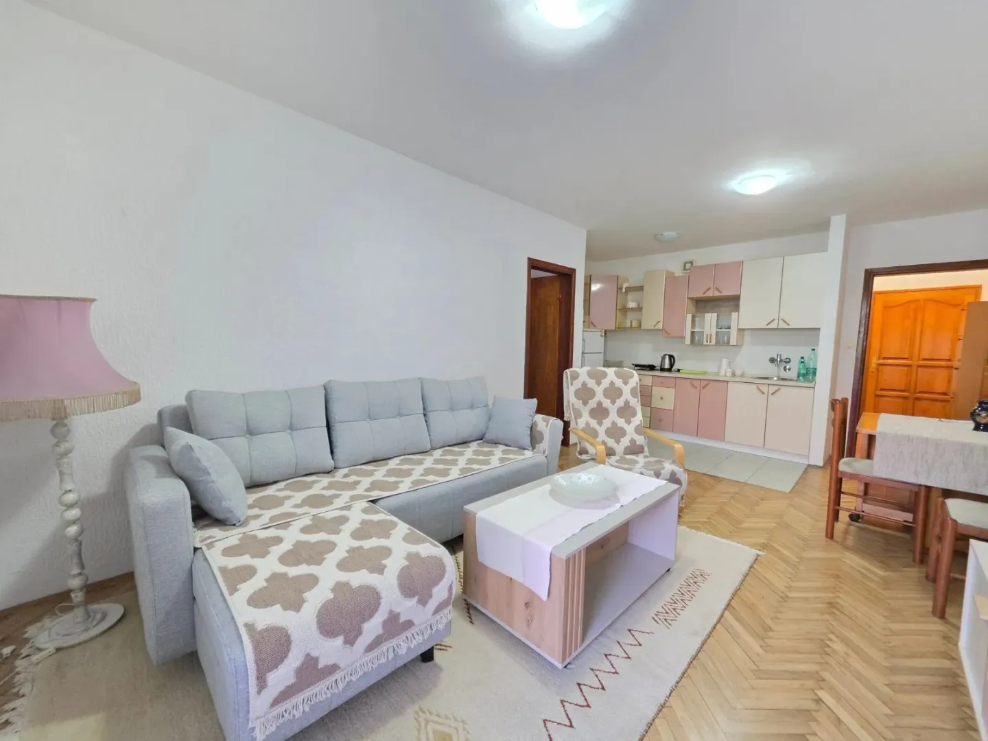 Living room with a corner sofa, coffee table, and kitchen in the background.