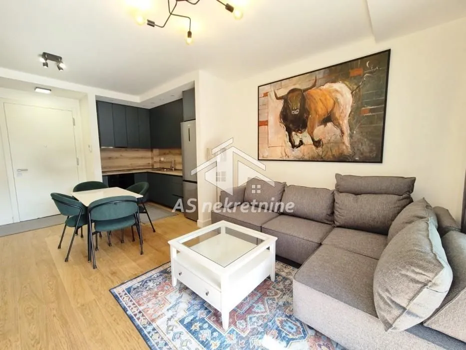 Living room with sofa, dining area, and kitchen in the background.