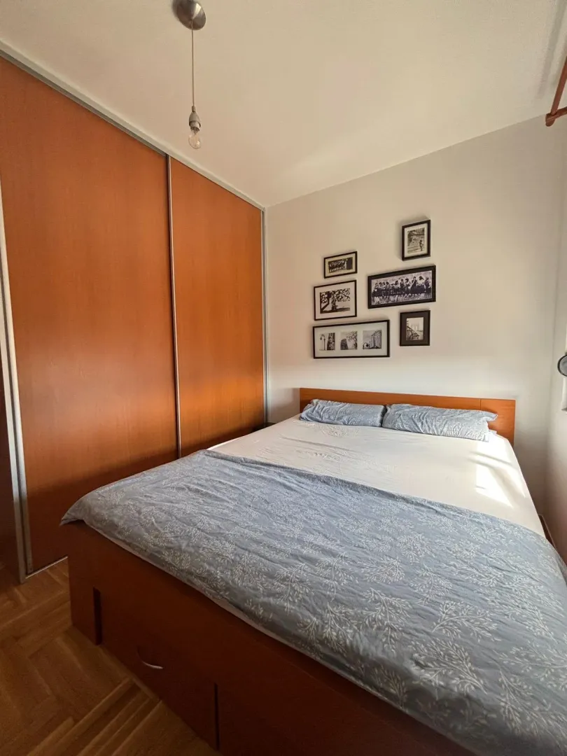 Namještena spavaća soba sa bračnim krevetom i ugradnim plakarom.