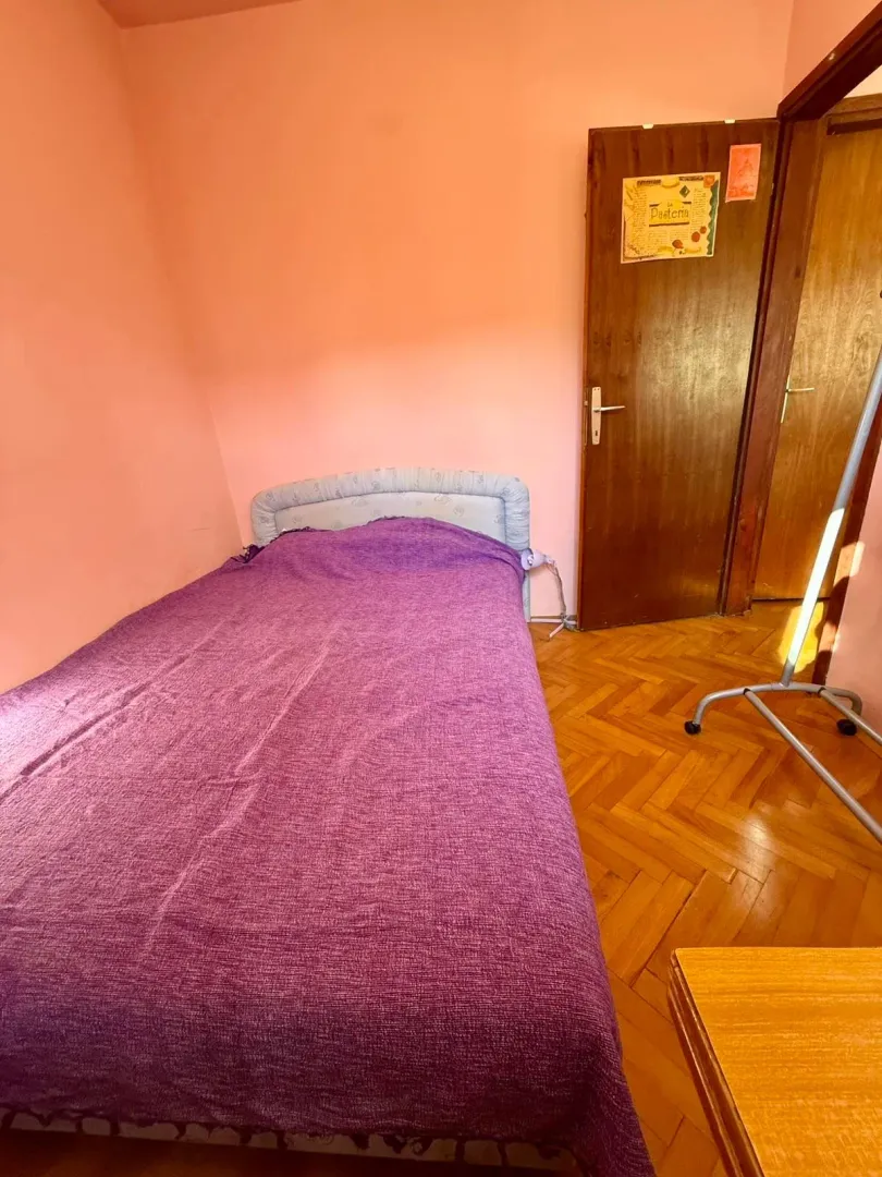 Manja spavaća soba sa krevetom i drvenim podom.