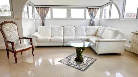 Living room with a white sectional sofa and large windows. - image 3