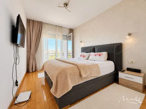 Namještena spavaća soba sa bračnim krevetom, noćnim stočićem, televizorom i izlazom na balkon. - image 7