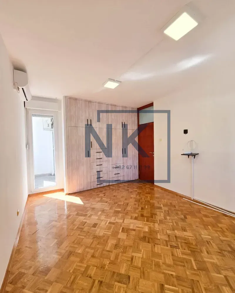 Empty bedroom with a built-in wardrobe and parquet flooring.