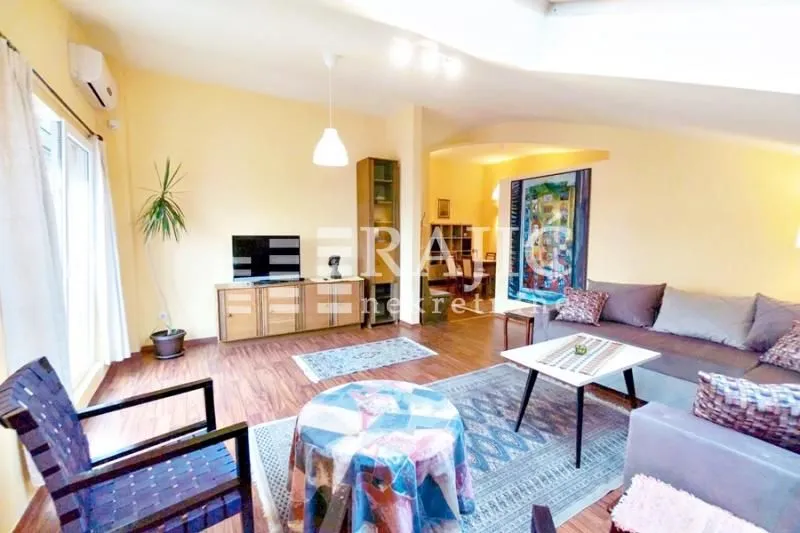 Spacious and bright living room with seating area and TV cabinet.