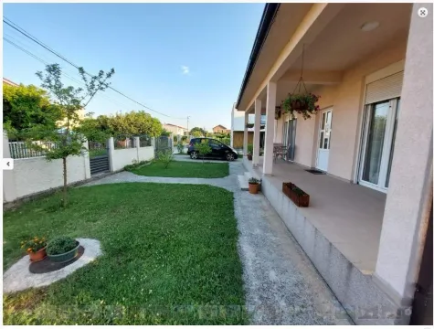 A landscaped yard with a green lawn and a spacious terrace in front of the house. - image 22