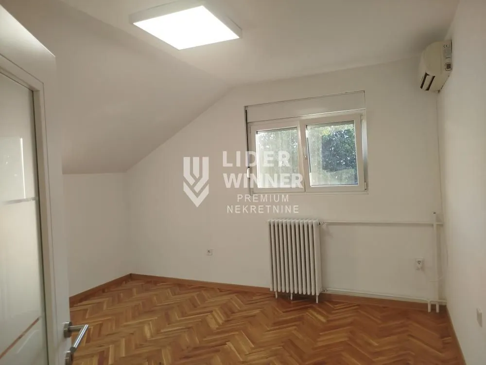 Empty room with wooden parquet flooring, white walls, and a sloped ceiling.