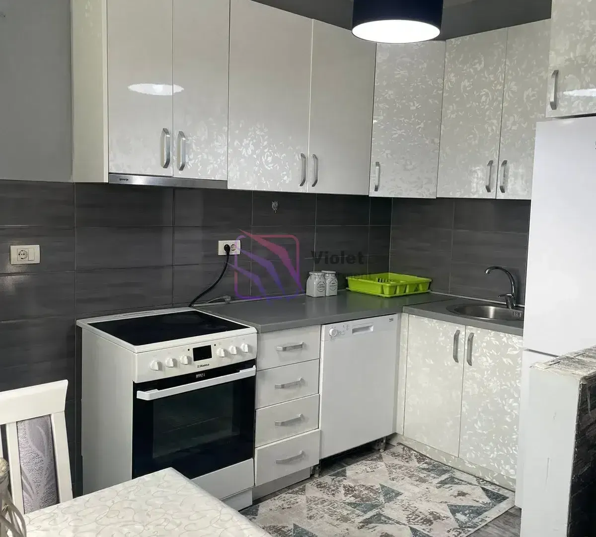 Kitchen with white cabinetry, stove, and sink.