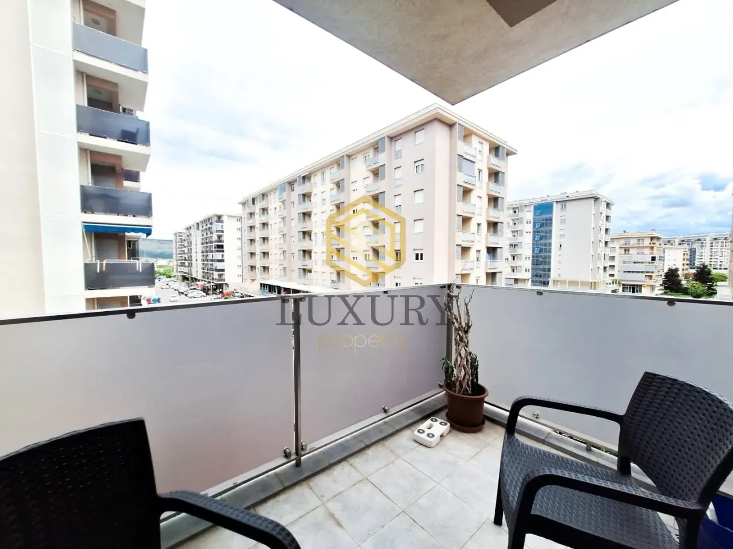 Namješten balkon sa garniturom za sjedenje i pogledom na okolne zgrade.