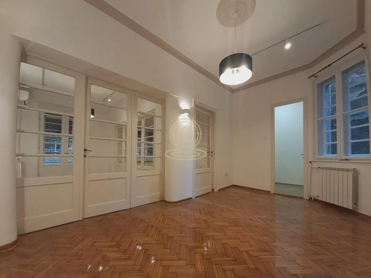 Empty living room with parquet flooring and white wooden doors.