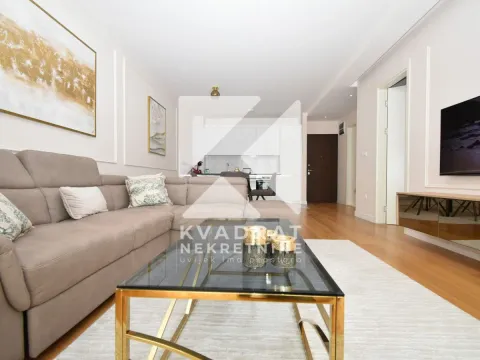 Living room with sofa, coffee table, and television, with a view of the kitchen. - image 2