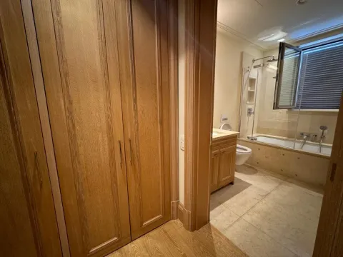 View from the hallway towards the bathroom with wooden elements and a bathtub. - image 7