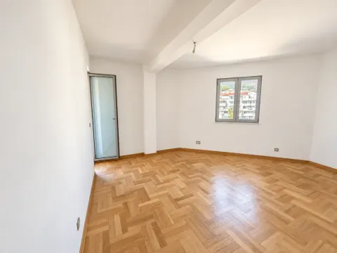 Empty room with white walls, wooden parquet flooring, a window, and a door. - image 10