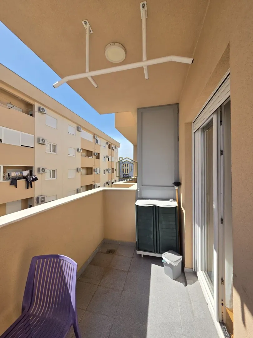 Manji namješten balkon sa pogledom na susjednu zgradu.