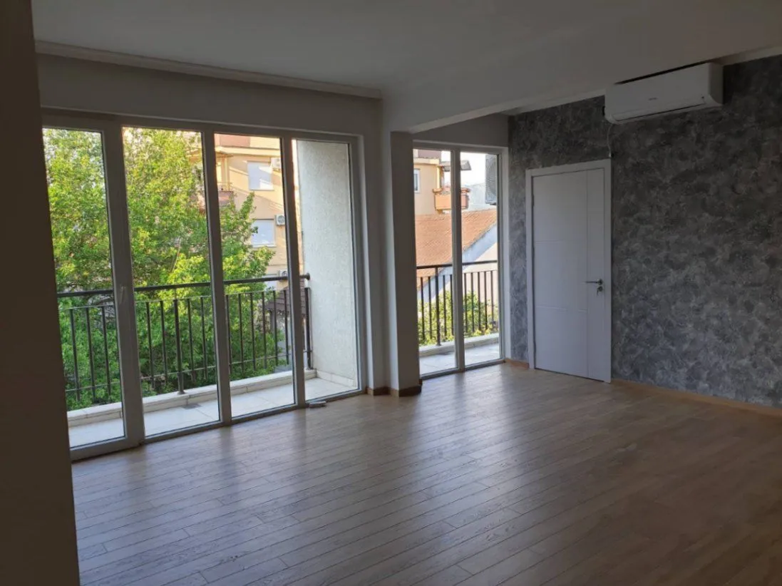 Bright empty room with access to a balcony and an air conditioner.