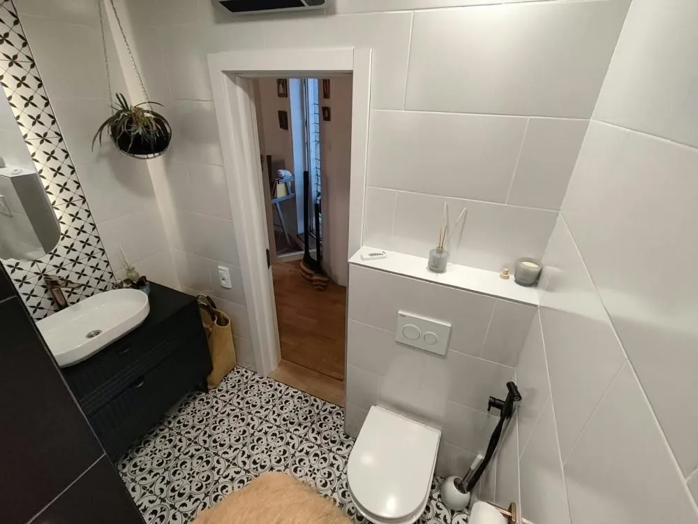 Moderno kupatilo sa umivaonikom, WC šoljom i dekorativnim pločicama.