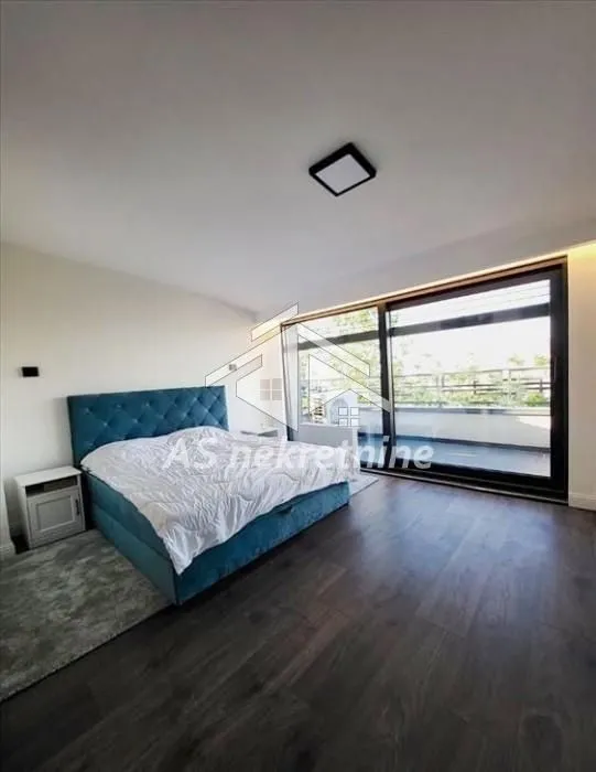 Bedroom with a double bed and a large glass wall overlooking the terrace.