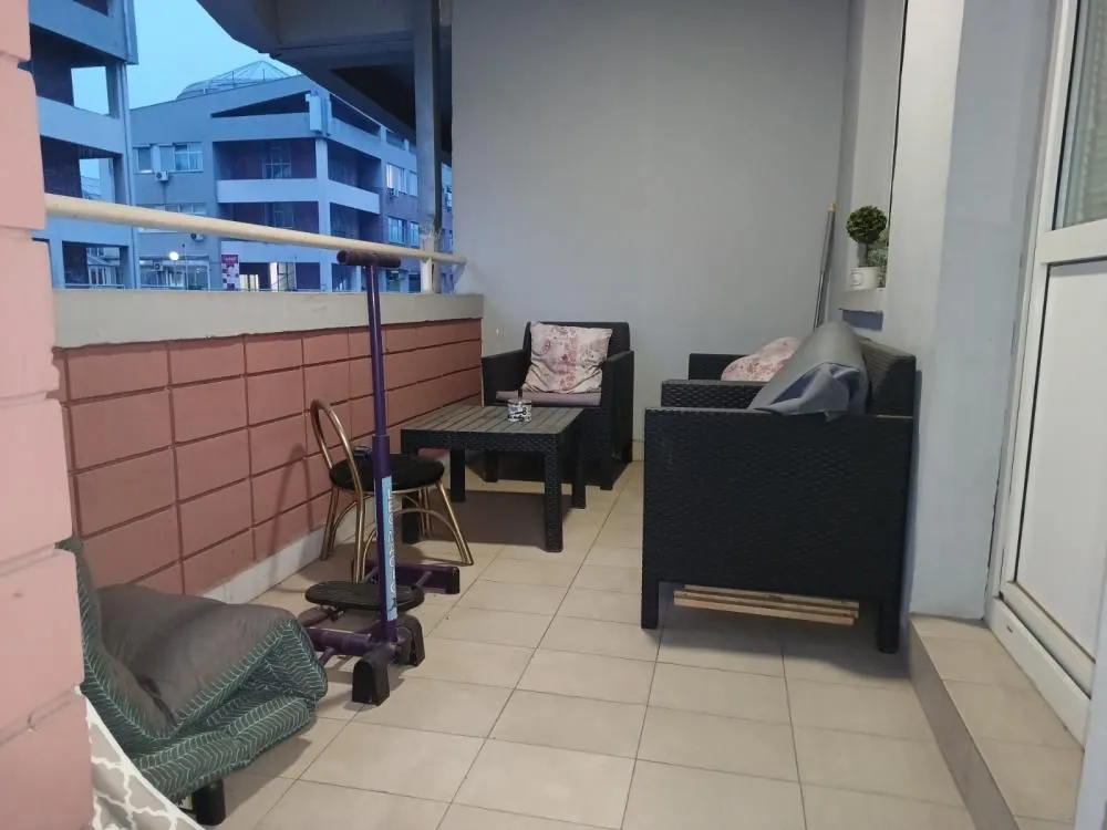 Nameštena terasa sa garniturom za sedenje i stolom.