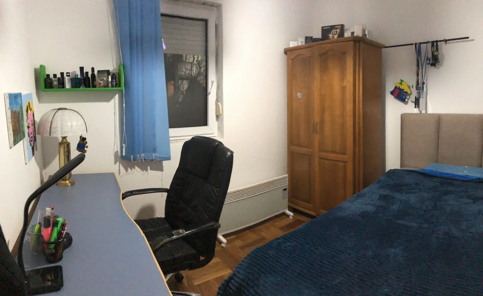 A furnished bedroom featuring a bed, desk, and wooden wardrobe.