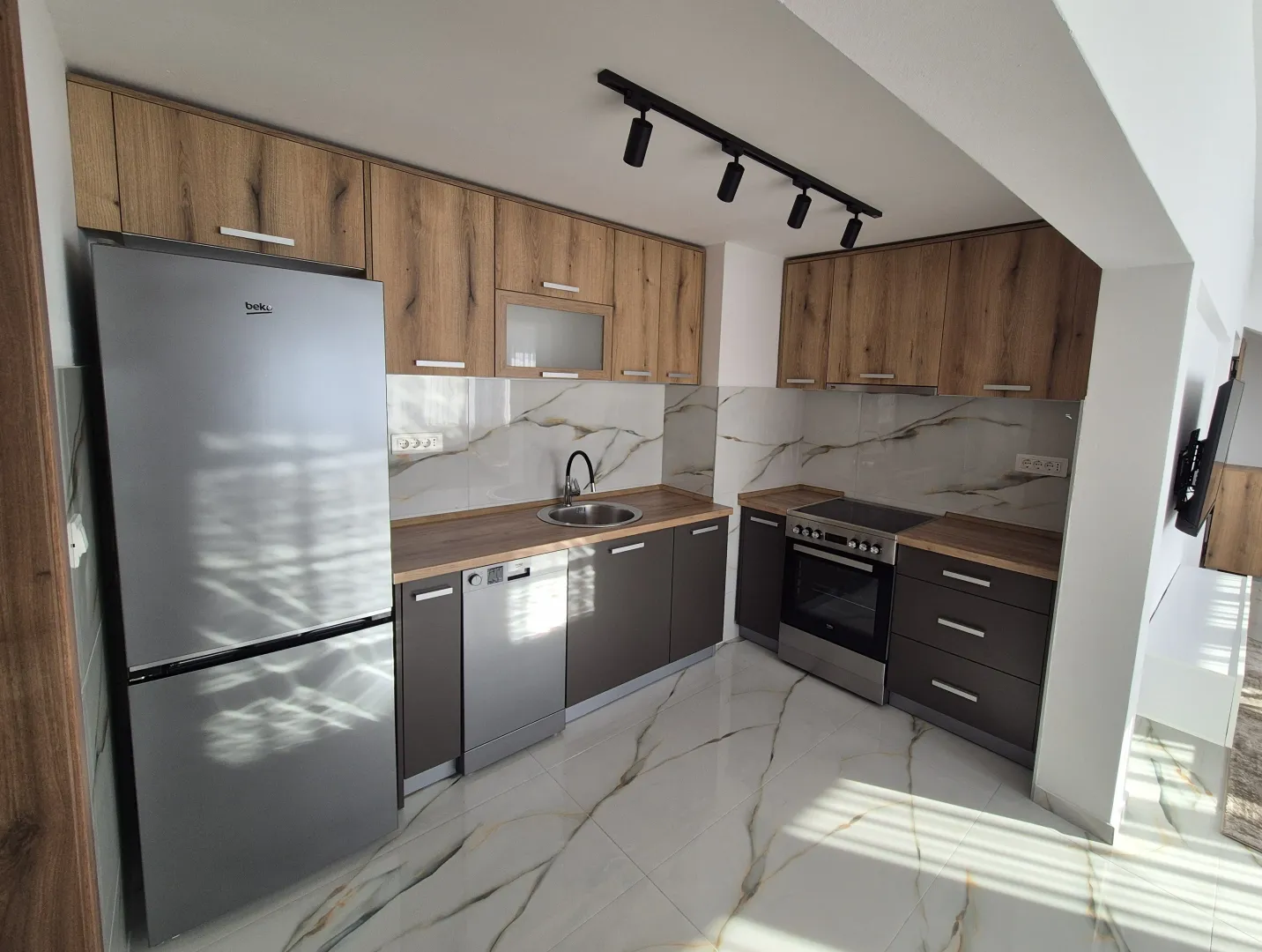 Modern kitchen with wooden cabinets, grey fronts, and built-in appliances.