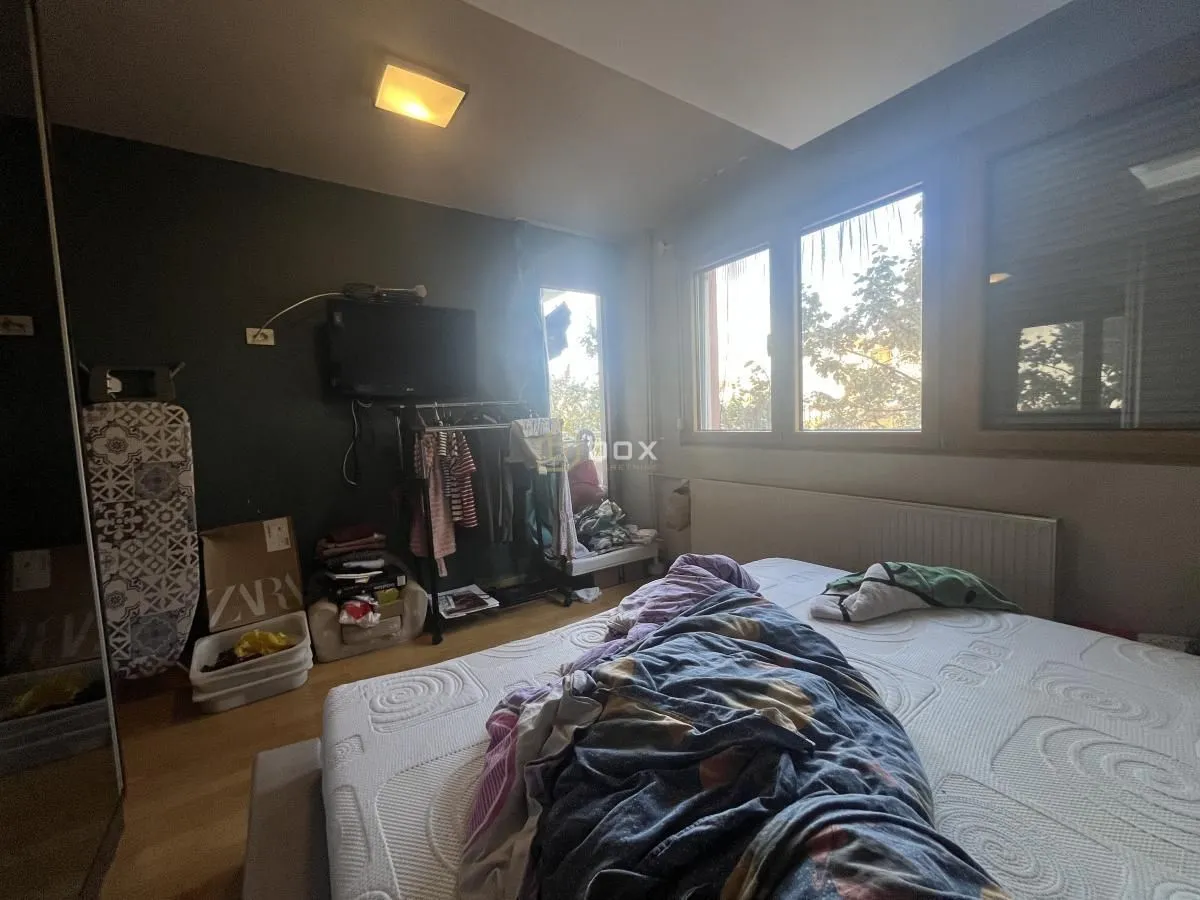 Spavaća soba sa krevetom i prozorima.