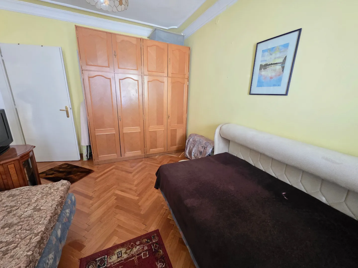 Furnished bedroom with a large wooden wardrobe and a bed.