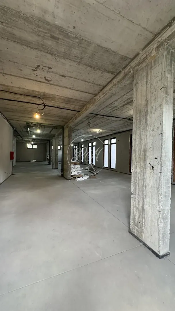 Large unfinished space in grey phase of construction with concrete pillars.