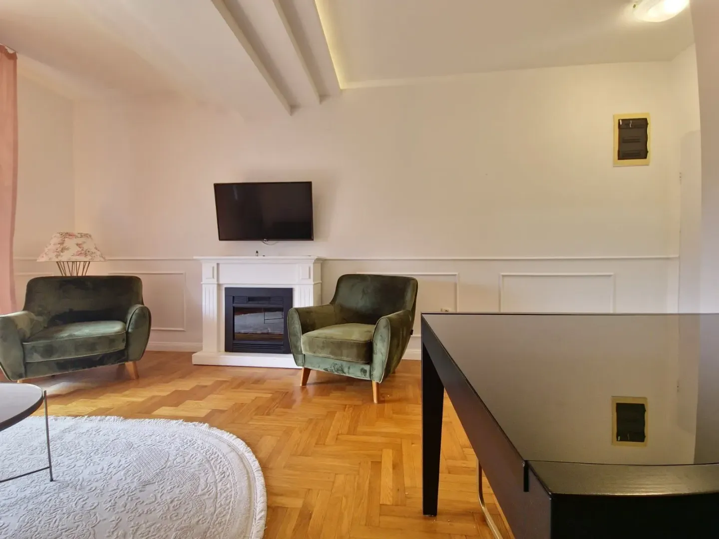 Living room with a fireplace, TV, and green armchairs.