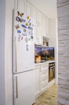 Small white kitchen with a refrigerator and built-in appliances. - image 4