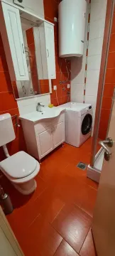 Bathroom with a shower cabin, sink, toilet, washing machine, and water heater. - image 5