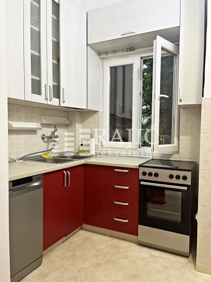 Small kitchen with red cabinets and a window.
