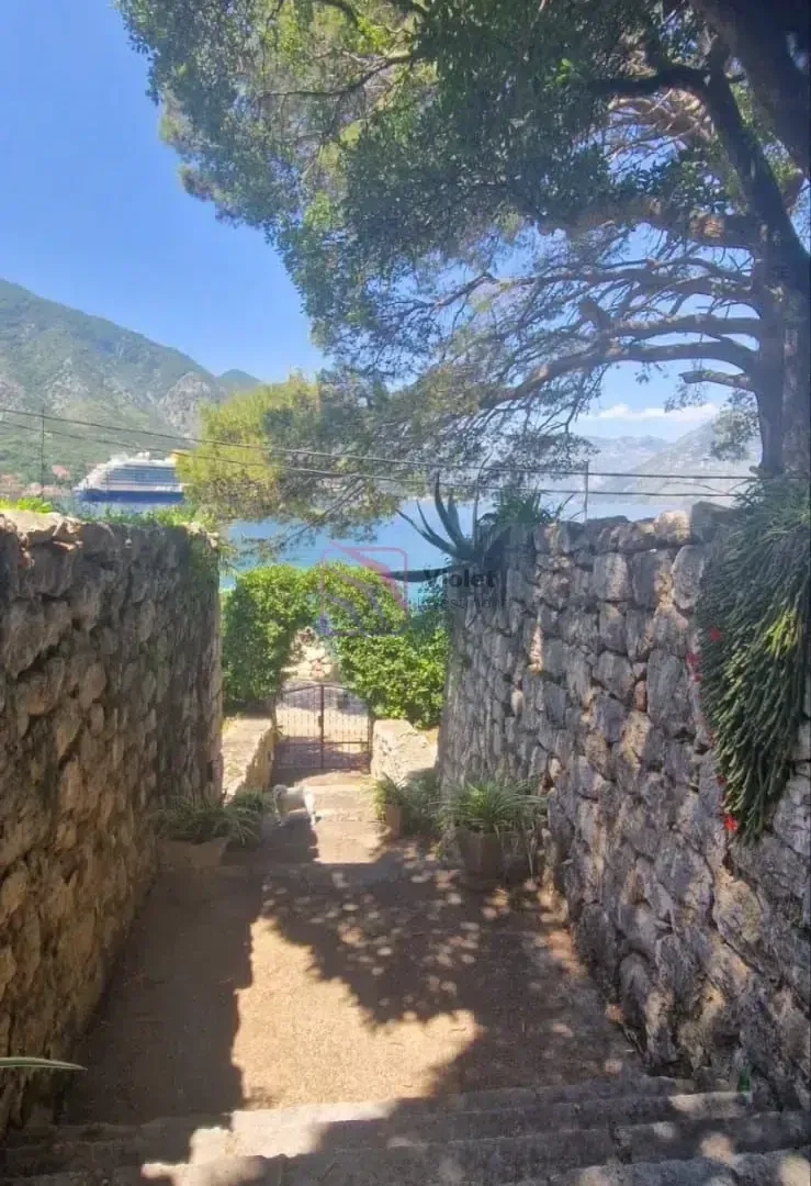 Kameno stepenište koje vodi prema moru i uređenom dvorištu sa zelenilom.