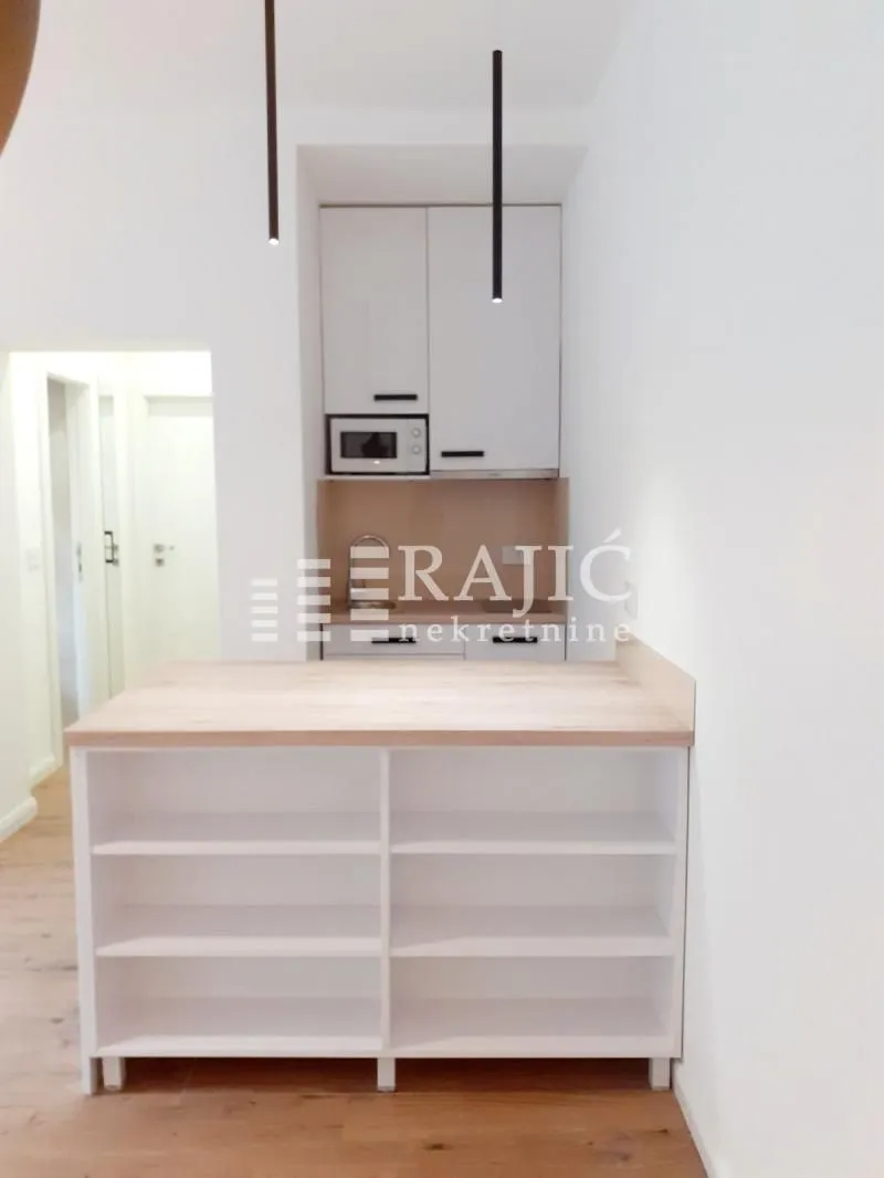 Modern kitchen with white units and a wooden bar.