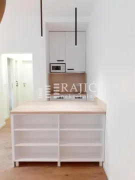 Modern kitchen with white units and a wooden bar. - image 4