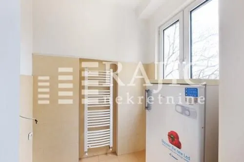 Small kitchen with a white refrigerator and towel radiator.