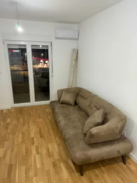 Dnevna soba sa braon trosjedom, drvenim podom i balkonskim vratima. - image 6
