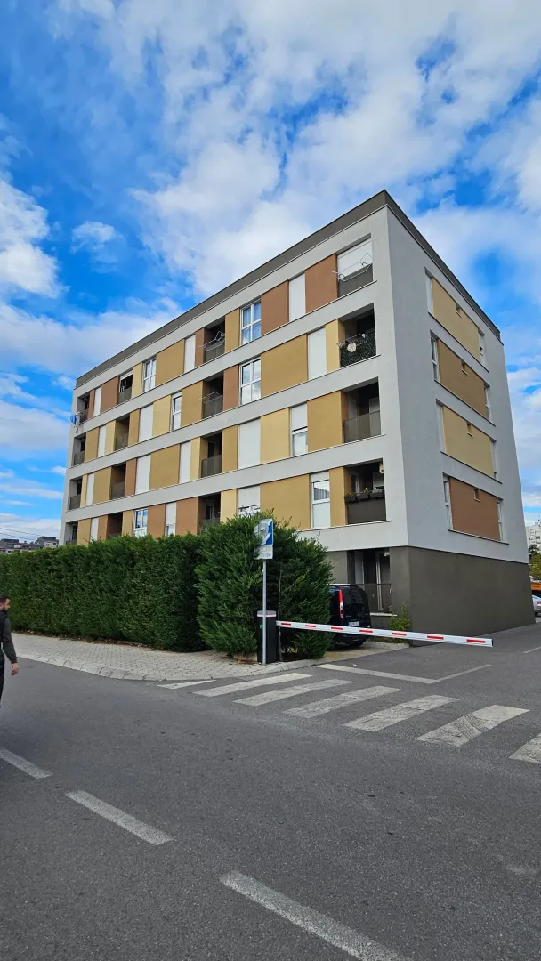 Exterior view of a modern residential building with balconies and a landscaped yard.