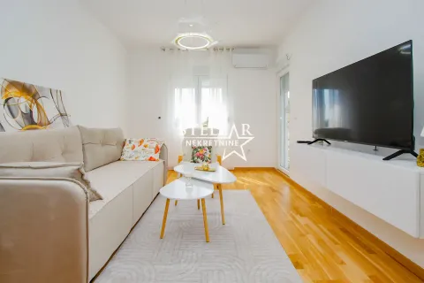 Svetao dnevni boravak sa garniturom, stočićem i televizorom na zidu. - image 2