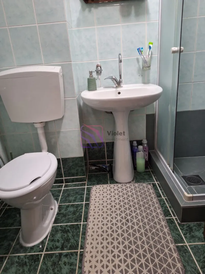 Kupatilo opremljeno umivaonikom, WC šoljom i tuš kabinom.