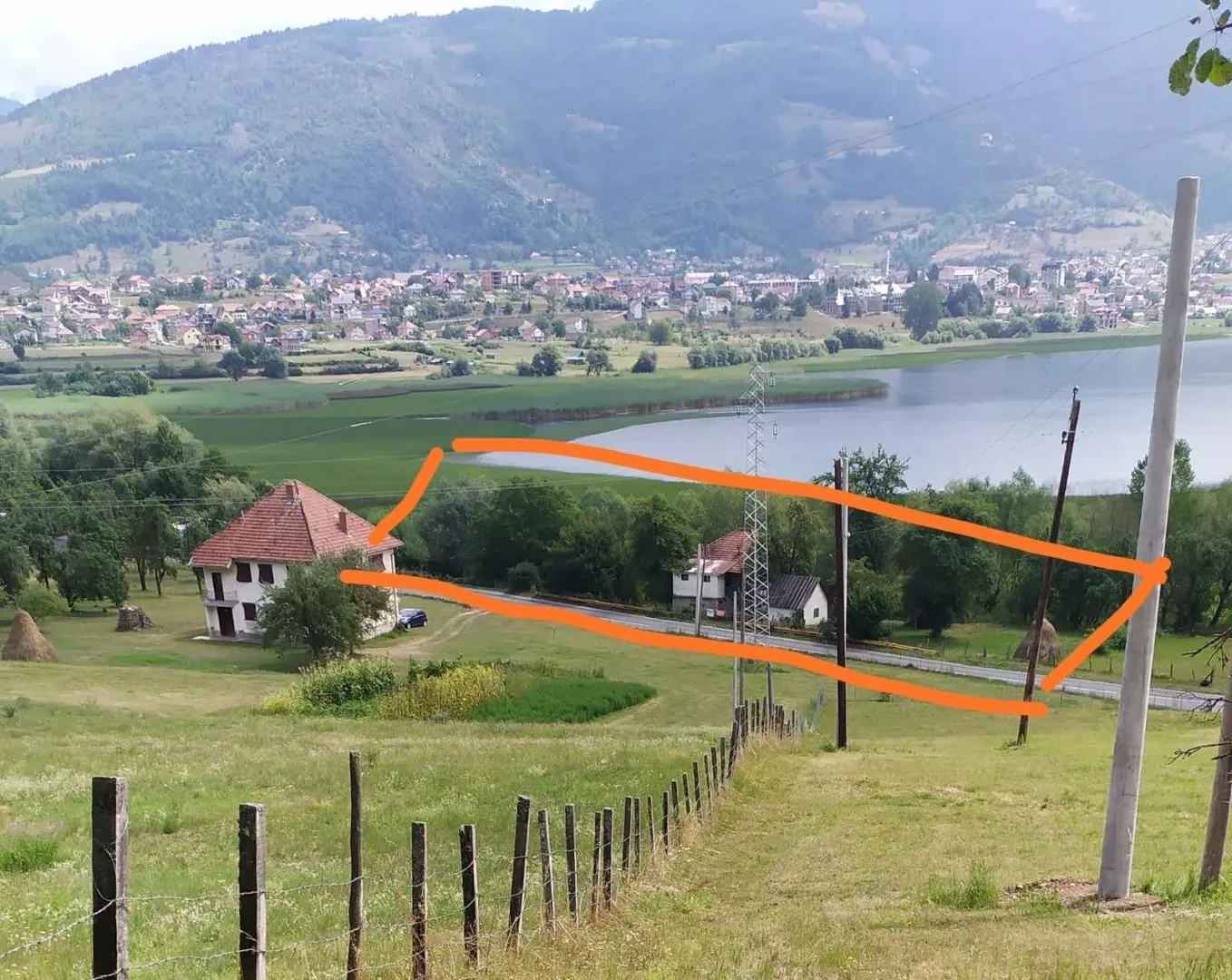 Pogled na zemljište i okolni pejzaž sa jezerom u daljini.