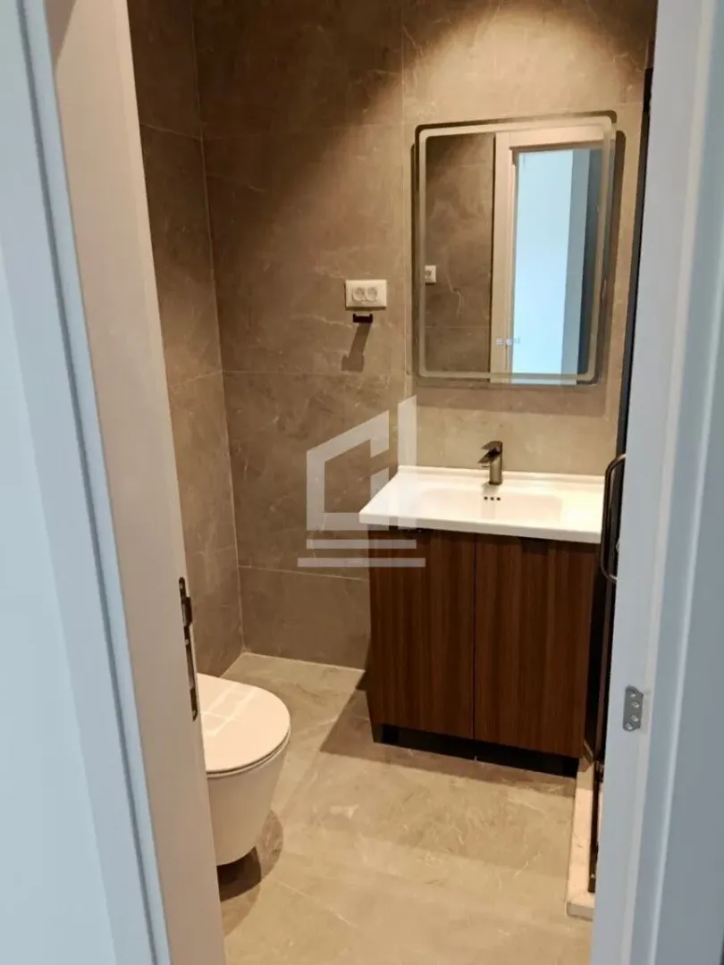 Pogled na moderno opremljeno kupatilo sa umivaonikom, ogledalom i WC šoljom.