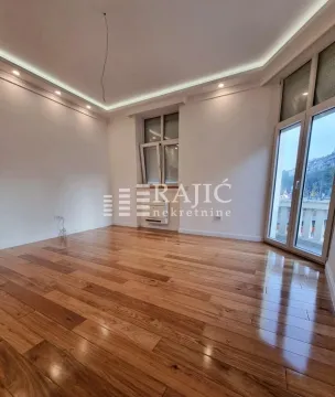 Empty living room with wooden flooring and large windows. - image 2