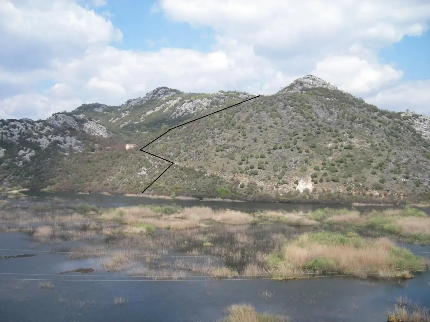 Pogled na brdoviti predio uz vodu sa iscrtanom linijom na pejzažu.