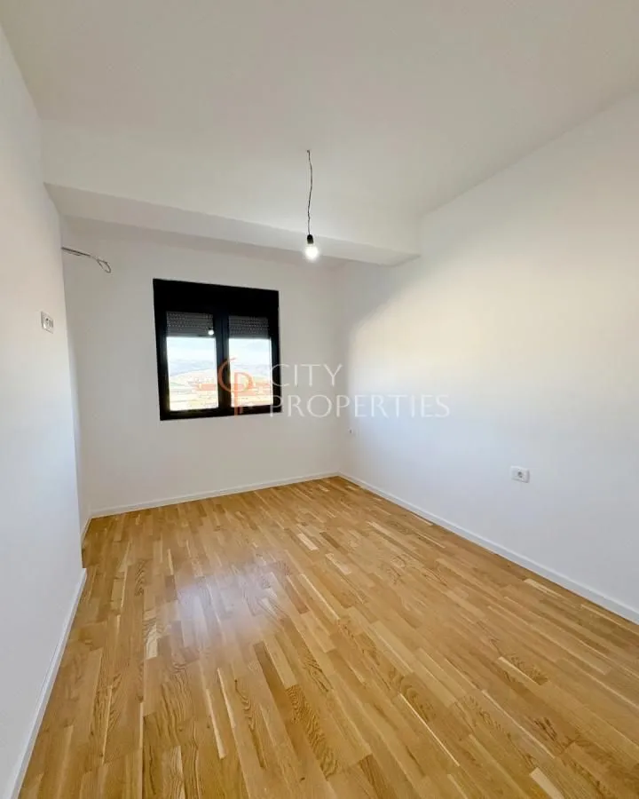 Empty room with white walls, parquet flooring, and a window.