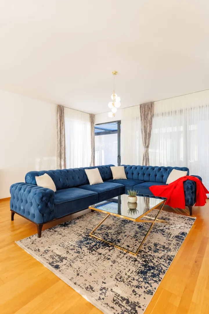 Living room with a large blue sofa and a glass coffee table.