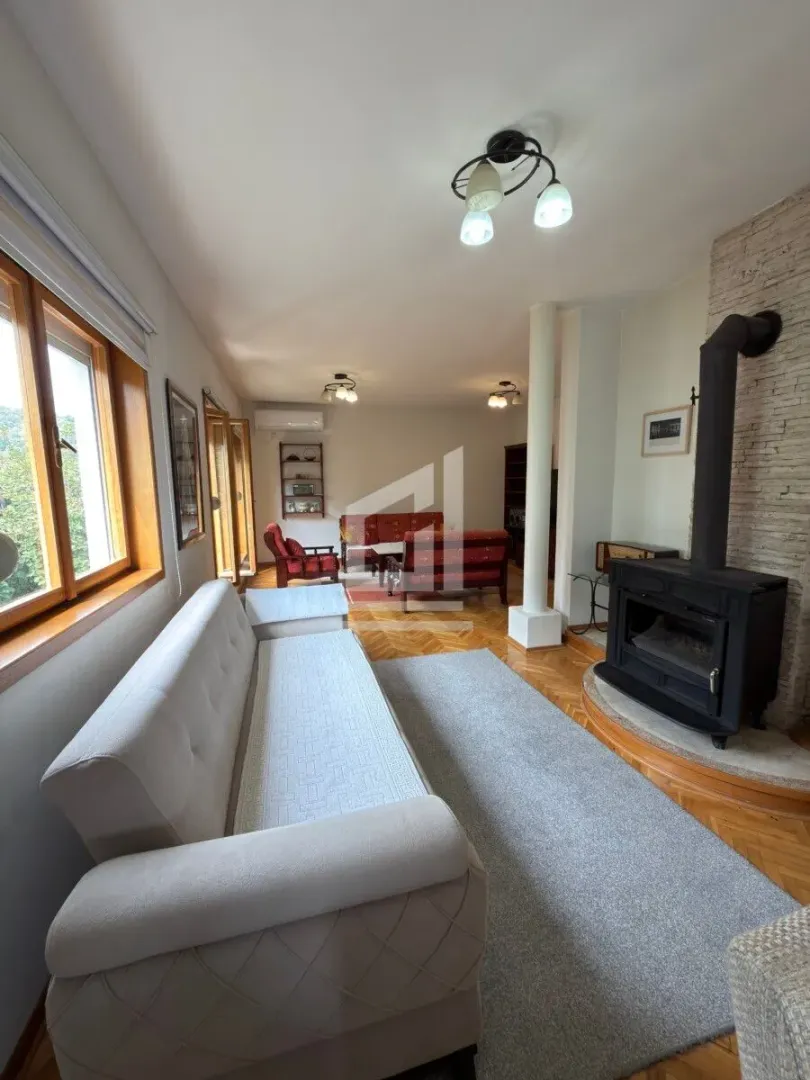 Spacious living room with seating furniture and a wood-burning stove.